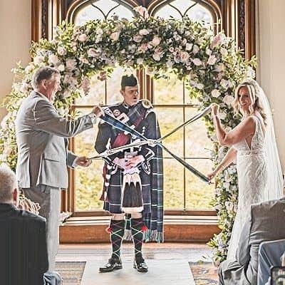 A Scottish wedding officiant conducting a handfasting ritual at a wedding